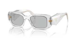 Occhiali da sole Prada PR 17WS Frosted Vanilla donna, montatura color vaniglia chiaro con lenti scure, posti su una superfici