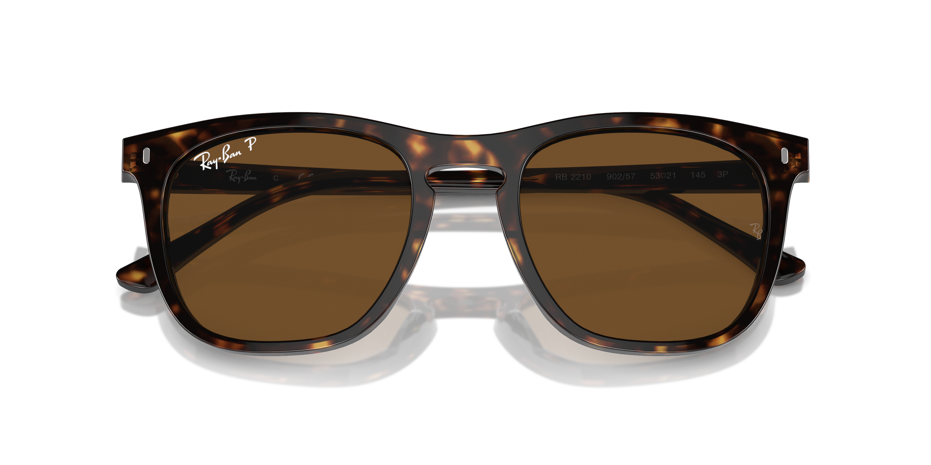 Occhiali da sole Ray-Ban RB2210 Frank con montatura trasparente e lenti verde scuro, posati su una superficie chiara.