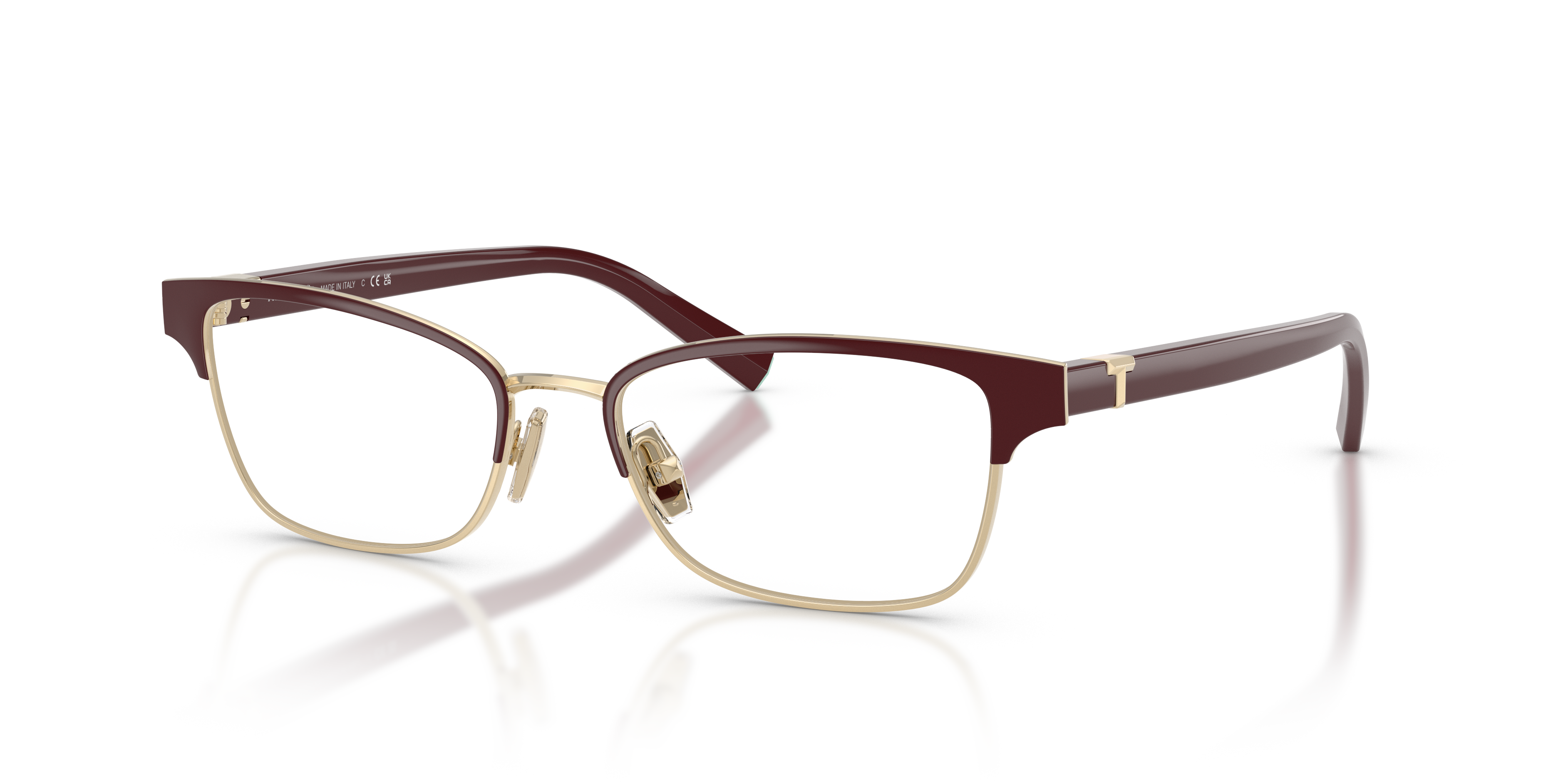 Occhiali da sole Tiffany TF1168 da donna, montatura bordeaux lucida con dettagli color oro pallido e lenti scure, posti su un