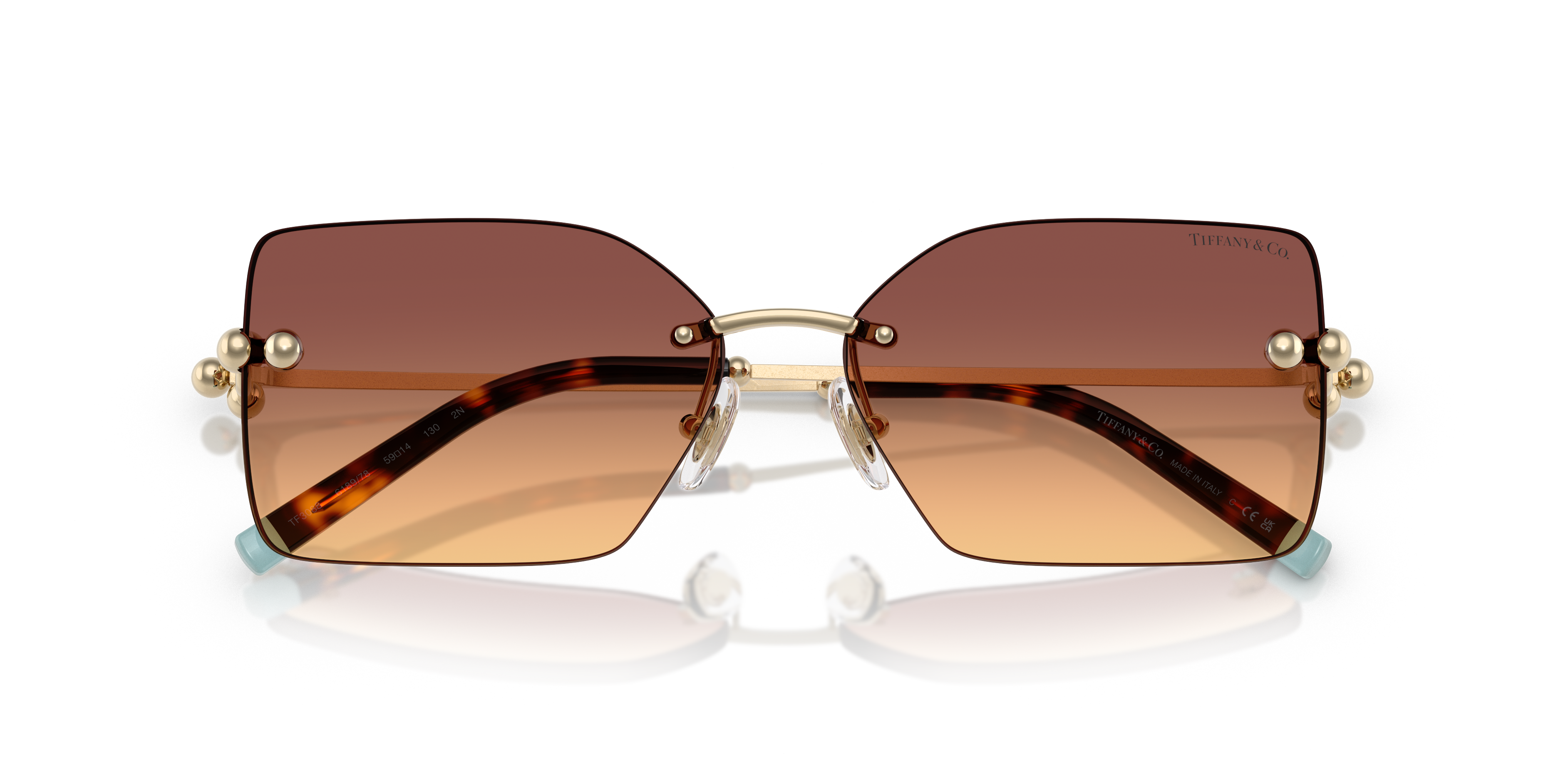 Donna che indossa occhiali da sole Tiffany TF3088 in colore Rubedo con lenti scure, montatura metallica rosa-oro e logo sulle