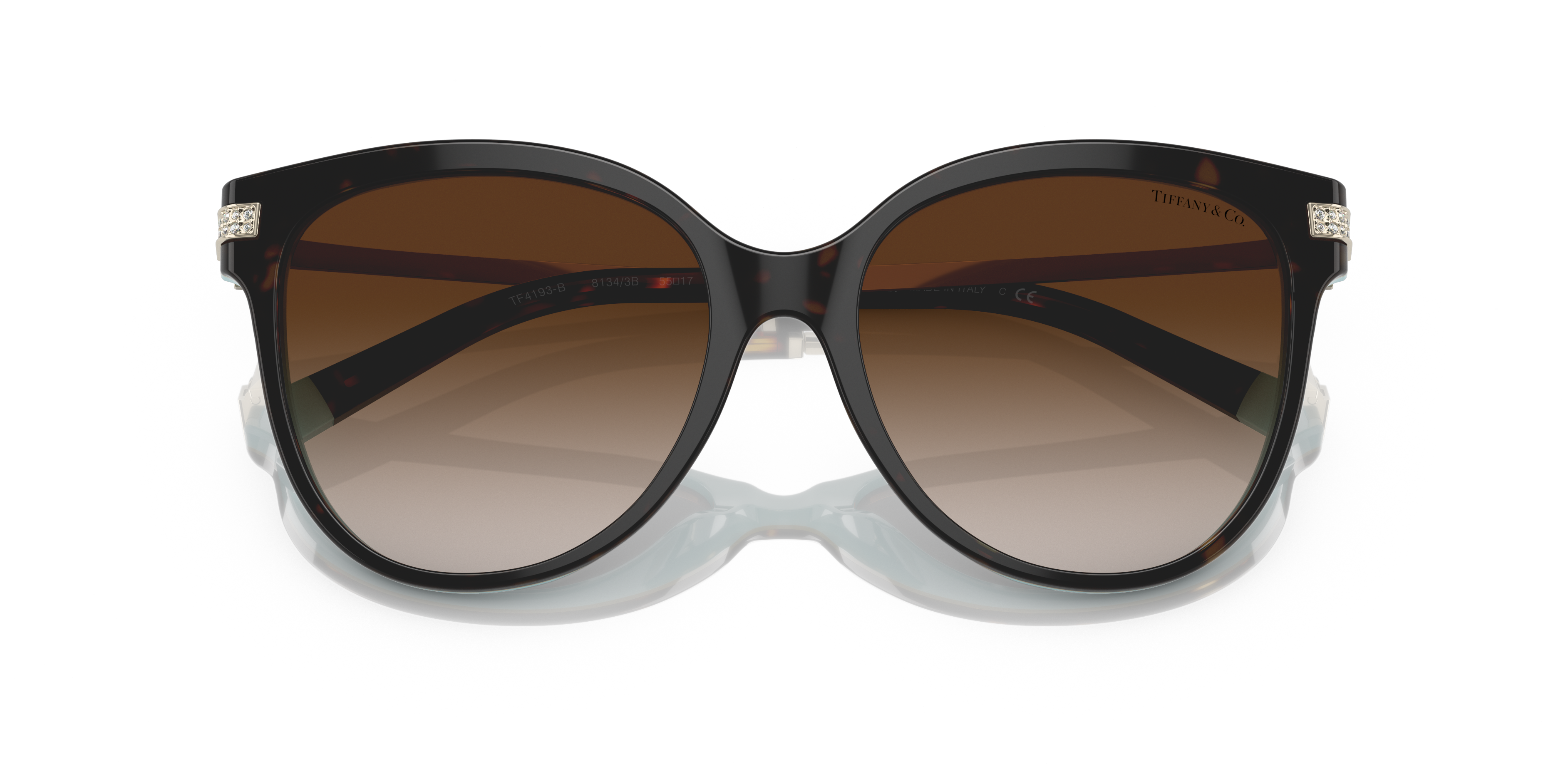 Occhiali da sole Tiffany TF4193B neri da donna con montatura cat-eye e dettagli in cristallo sulle aste, appoggiati su una su