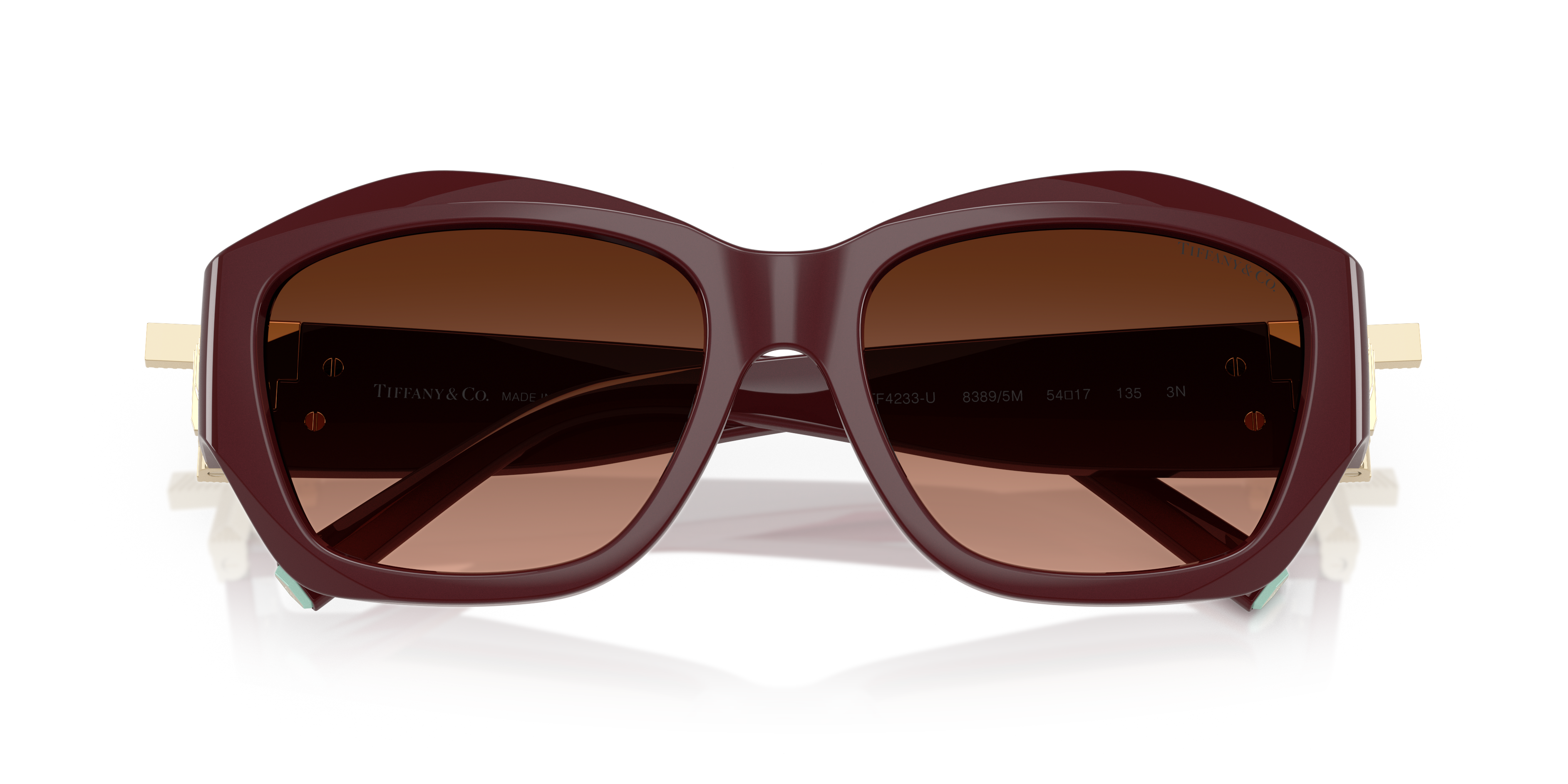 Occhiali da sole Tiffany TF4233U da donna in colore Havana con montatura squadrata e aste decorate, appoggiati su una superfi