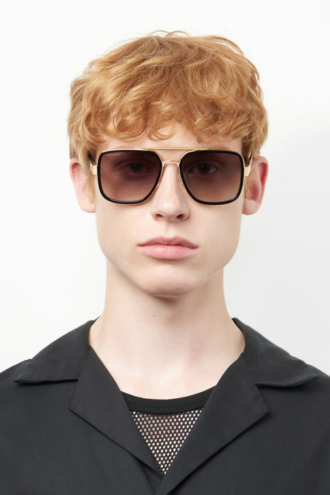 Occhiali da sole DSQUARED2 D2 0060/S da uomo, con montatura in metallo color oro lucido e lenti scure, mostrati su sfondo bia